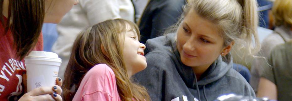 Student with her smiling Bona buddy at a basketball game.